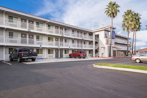 A motel with a two-story structure, a parking lot, and a few vehicles.