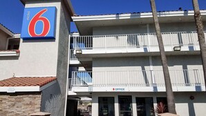 A motel with a prominent sign, multiple balconies, and an office sign.