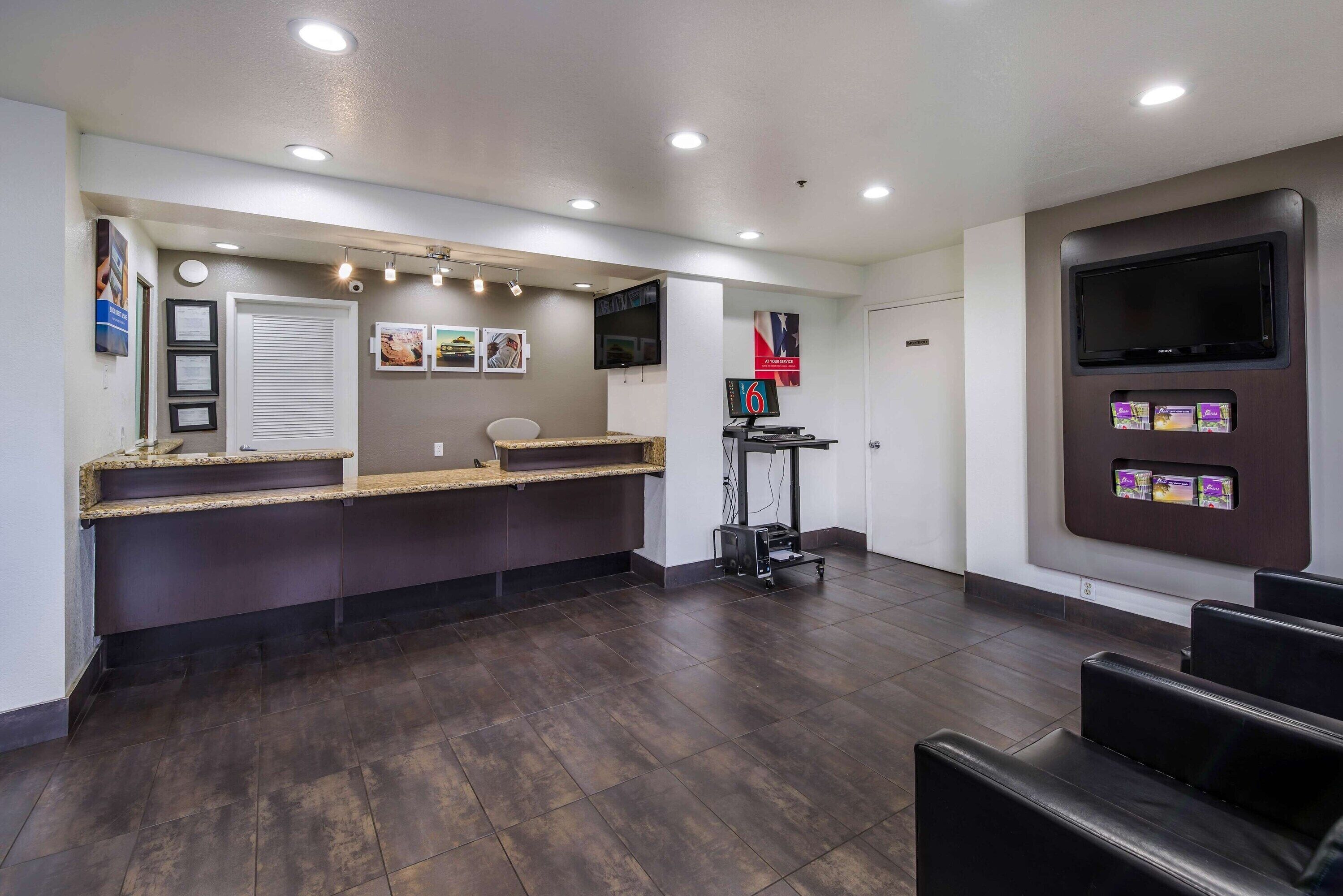A reception area with a counter, seating, a TV, and a wall-mounted display.