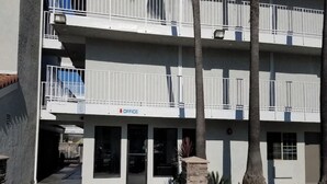 A multi-story building with a sign indicating an office on the ground floor.