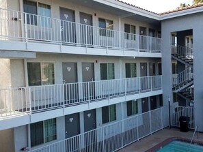 Un edificio de varios pisos con balcones, piscina y una escalera.