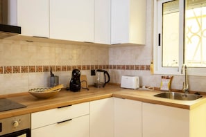 Eine Küche mit weißen Schränken, einer Kaffeemaschine, einem Toaster und einem Spülbecken.