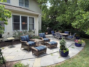 Eine Terrasse mit Korbmöbeln, einem Tisch und Topfpflanzen.