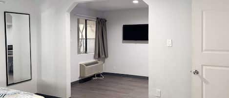 Une chambre avec deux lits, une fenêtre avec des rideaux, un téléviseur fixé au mur et un radiateur.