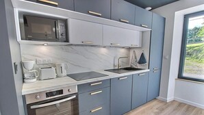 Una cocina moderna con gabinetes grises, microondas integrado, cafetera, tostadora y un lavamanos.