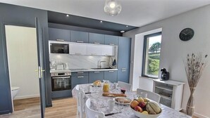 Una cocina moderna con armarios grises, encimera de mármol y comedor con mesa preparada para el desayuno.