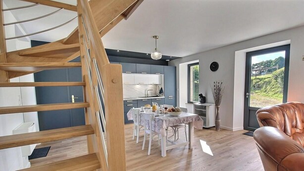 Una cocina moderna con comedor, una escalera y vistas al exterior.