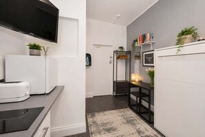 Eine moderne Küche mit Flachbildfernseher, Backofen und Kaffeemaschine.