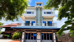 A multi-story building with a central staircase, a covered entrance, and a tiled ground floor.