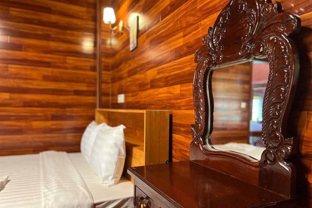 Quarto com painéis de madeira, uma cama, cômoda e espelho.