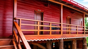 Ein rotes Holzgebäude mit einem Balkon, Holzbalkonen und einer Treppe, die zum Eingang führt.