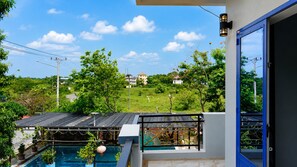 Il s’agit d’une propriété résidentielle dotée d’une piscine, d’un balcon avec une balustrade et offrant une vue sur un paysage verdoyant, avec des maisons visibles au loin.