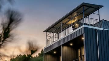 Een modern gebouw met een balkon, een trap en een groot raam.