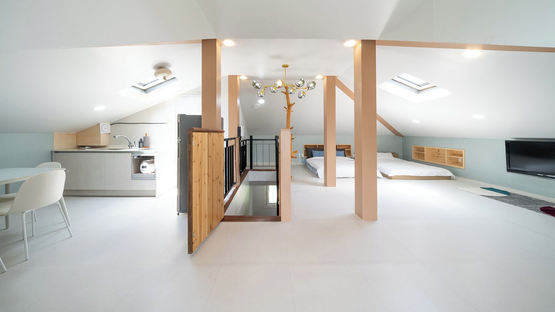Un dormitorio moderno estilo loft, con techo inclinado, televisión integrada y escalera que conduce a un nivel superior.