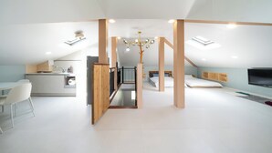 A modern loft-style bedroom with a sloped ceiling, a built-in TV, and a staircase leading to an upper level. - Gyeongju Cheongbori Stay Pension (Gyeongju)