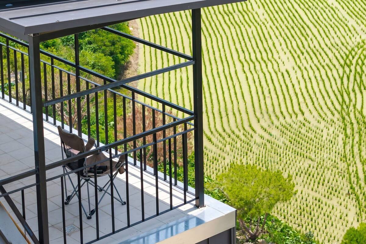 Ein Balkon mit Blick auf ein ordentlich angelegtes Feld.