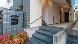 A building entrance with a staircase, a fire extinguisher, and a sign with Japanese characters. - Kag.R Ohori 3  (Fukuoka)