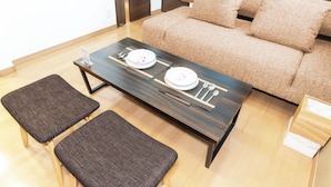 A modern living room with a sofa, two chairs, a coffee table, and a dining table set with plates and cutlery. - Kag.R Ohori 3  (Fukuoka)