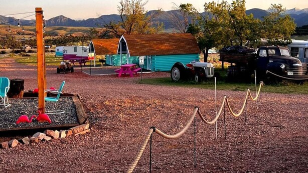 A campsite with RVs, a small building, and a fenced area with flamingos.