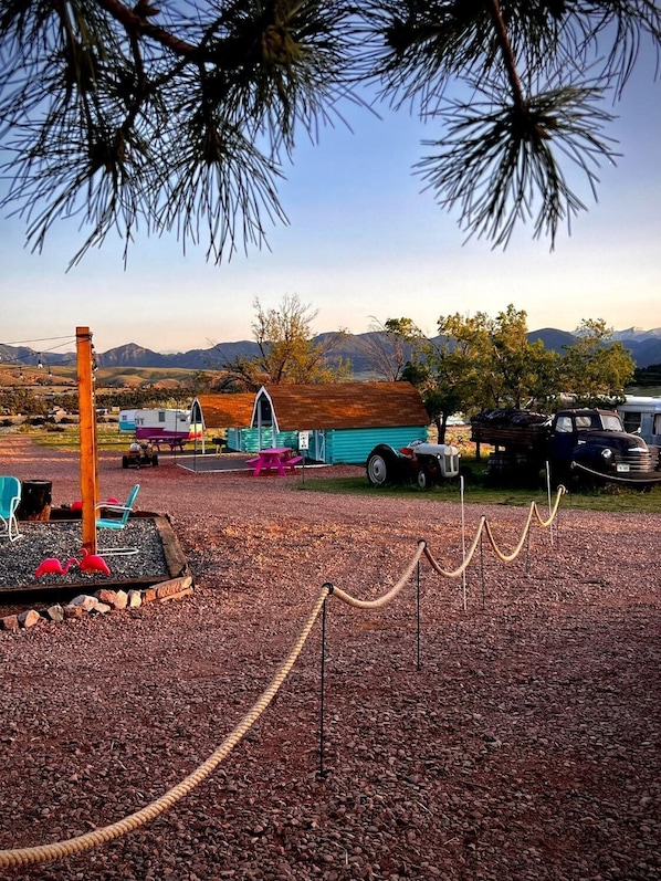 A campsite with RVs, a small building, and a fenced area with flamingos.