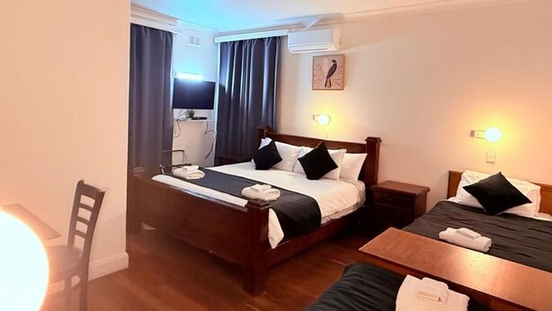 A hotel room with a bed, bedside tables, a desk, and a chair. - Coonalpyn Hotel (Coonalpyn)