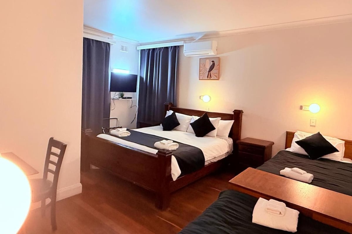 A hotel room with a bed, bedside tables, a desk, and a chair.