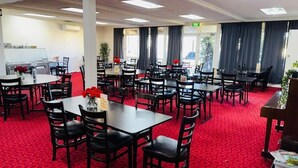 A hotel dining area with multiple tables and chairs, a red carpet, and a kitchen area in the background. - Coonalpyn Hotel (Coonalpyn)