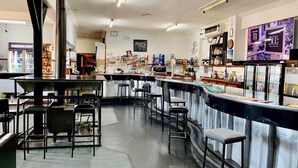 A bar area with stools, a counter, and a large black heater. - Coonalpyn Hotel (Coonalpyn)