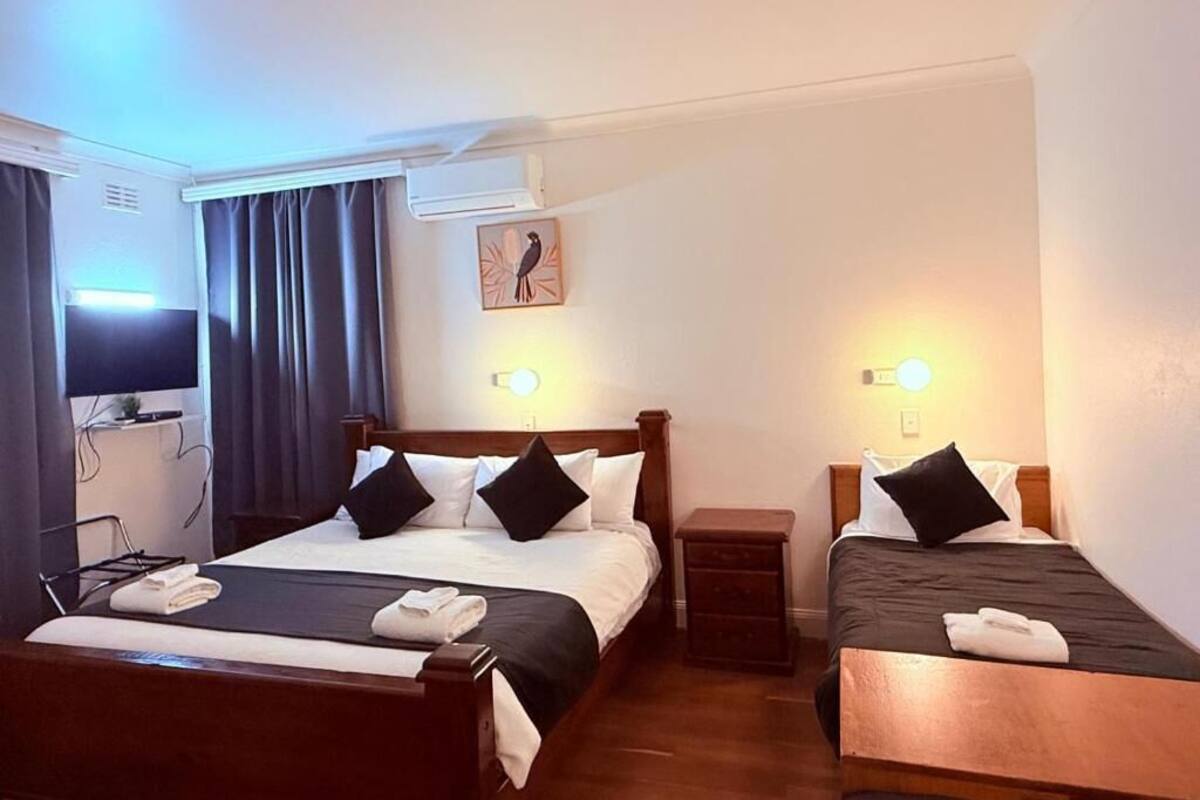 A hotel room with two beds, a TV, a desk, and a small table.