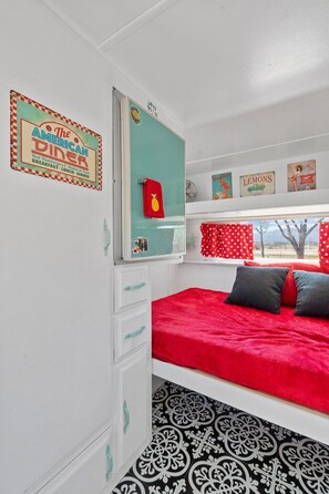 Ein Schlafzimmer mit Bett, Kommode, Spiegel und einem Fenster mit Blick.