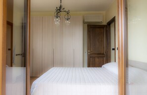 Une chambre à coucher comprenant un lit, une armoire en bois, une porte et un luminaire au plafond.