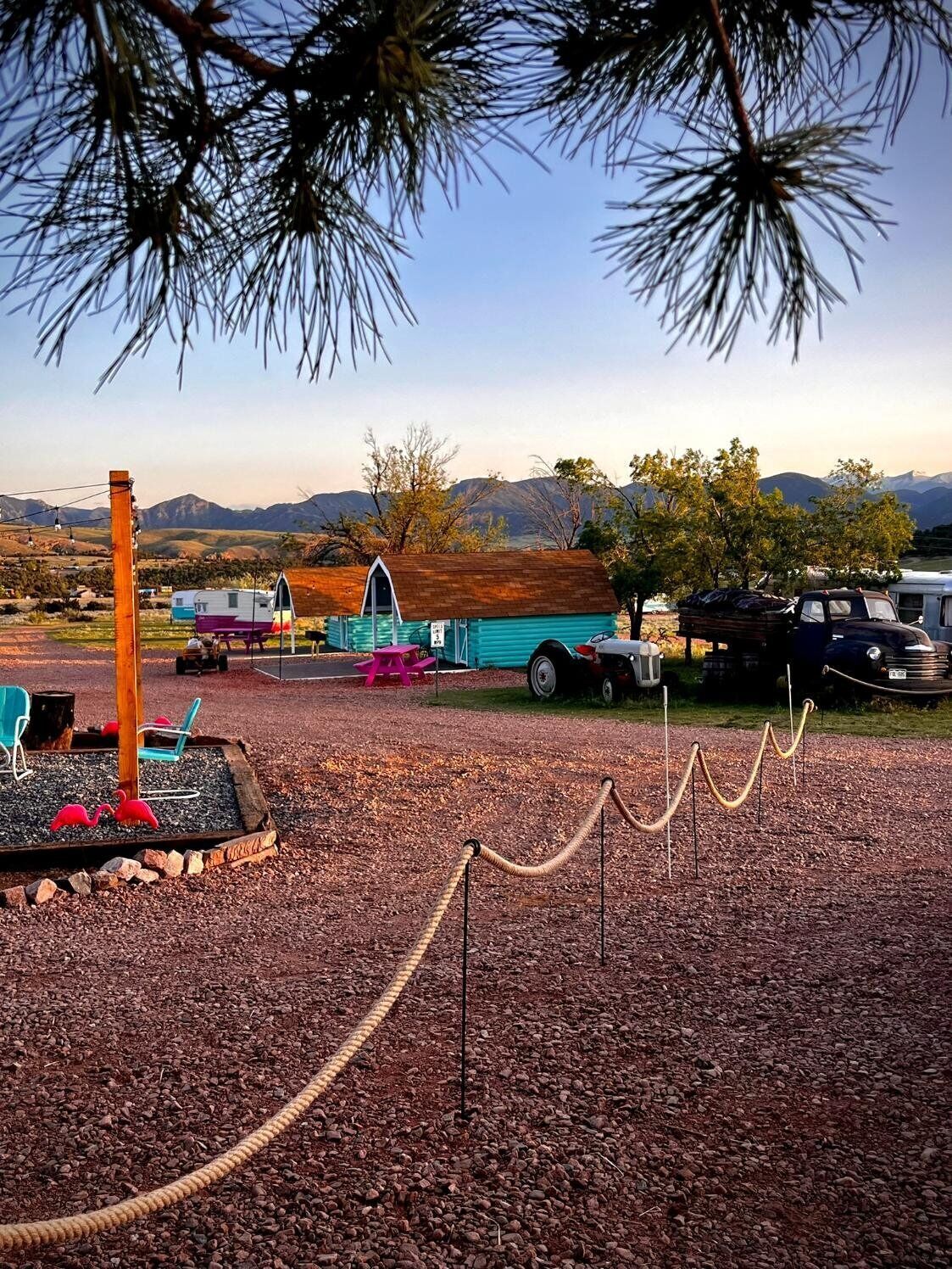 Un camping con vehículos recreativos, un edificio pequeño y un área cercada con flamencos.