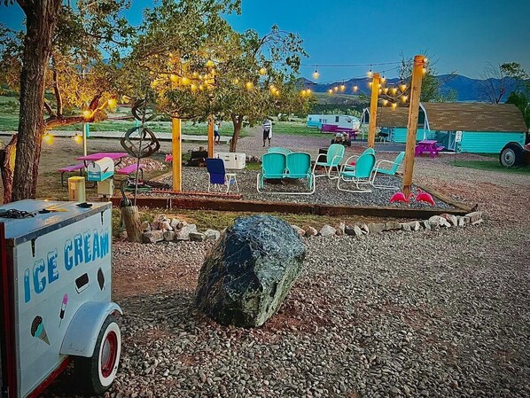Un espace extérieur aménagé avec des chaises, un rocher et un chariot à glaces.