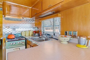 Cocina compacta con estufa, lavamanos y ventana.