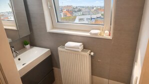 Un baño con ventana, lavabo, espejo, radiador y barra para toallas.