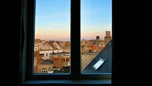 Vista a través de una ventana de un paisaje urbano con edificios y cielo despejado.