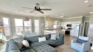 A spacious living room with a sectional sofa, a small armchair, and a ceiling fan.