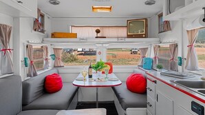 Interior compacto de autocaravana con kitchenette, zona de estar y televisor.
