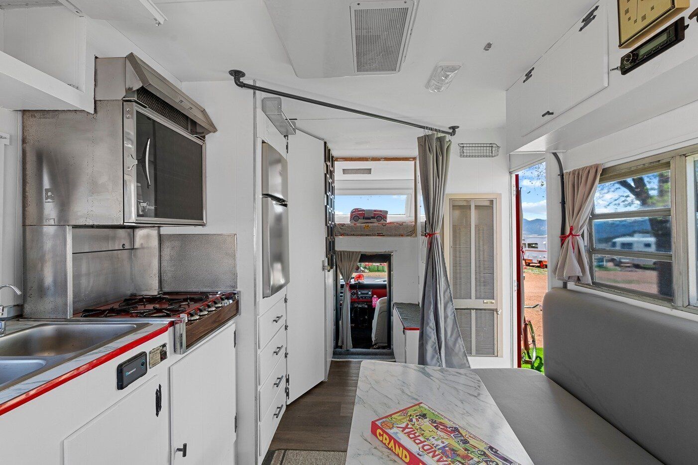 A compact RV kitchen with a stove, sink, and a small dining area.