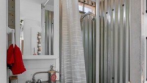 Un baño pequeño con lavamanos, espejo, cortina de ducha y retrete.
