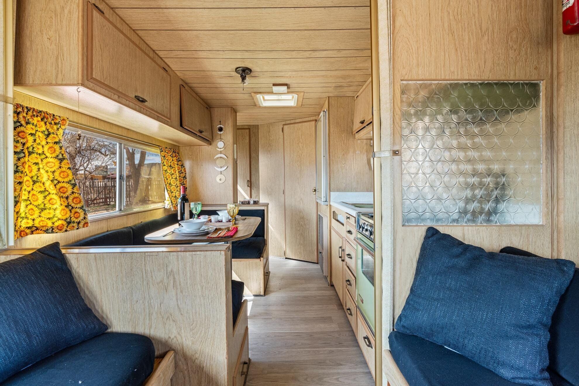 A compact RV interior with a kitchenette, dining area, and seating.
