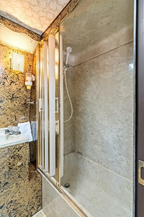 Une salle de bain avec une douche à parois de verre, un lavabo en marbre et un porte-serviettes.