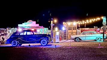 Vanhoja autoja on pysäköitynä rakennuksen eteen, ja rakennuksessa on neonvaloilla varustettu kyltti.