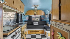 Ein kompaktes Wohnmobil-Interieur mit Küchenzeile, einem Bett und einem kleinen Badezimmer.