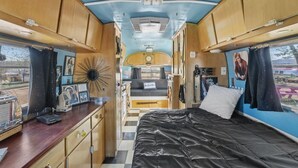 Ein kompaktes Wohnmobil-Interieur mit Bett, Küchenzeile und einer kleinen Essecke.