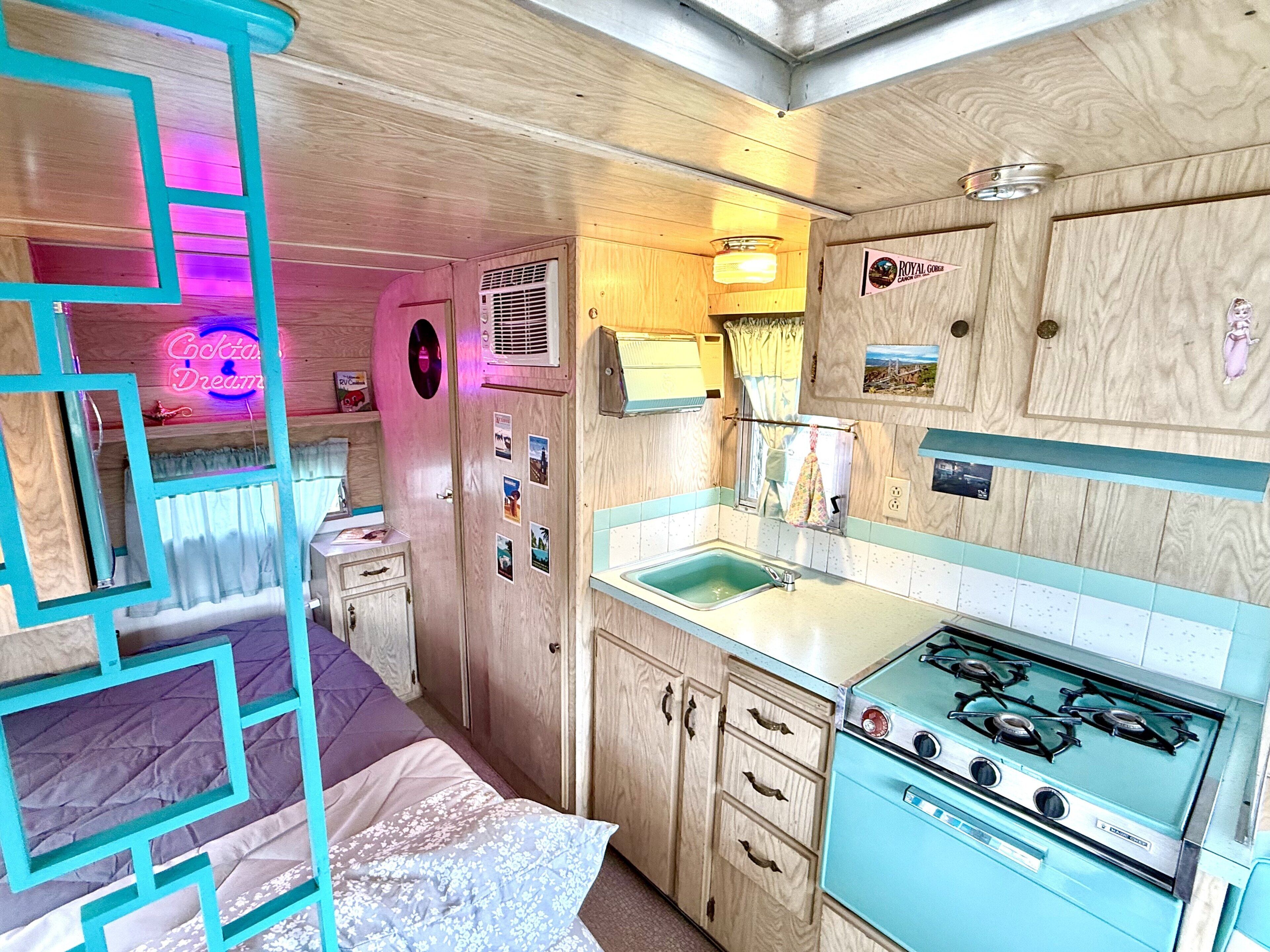 A compact RV kitchen with a stove, sink, and wooden cabinets.
