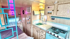 Cocina compacta para autocaravana con estufa, fregadero y armarios de madera.
