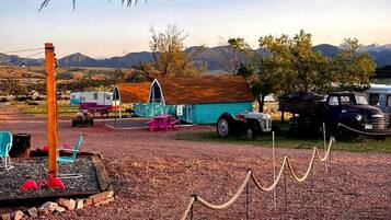 A campsite with RVs, a small building, and a fenced area with flamingos.