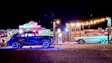 Vintage cars parked in front of a building with a neon sign.