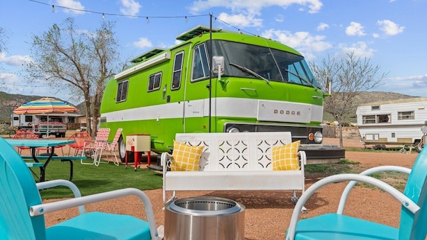 A green recreational vehicle with a Dodge logo, a barbecue grill, and outdoor seating with turquoise chairs. - Vintage Motorhome Stay | Unique Experience | Cañon City, CO (Canon City)
